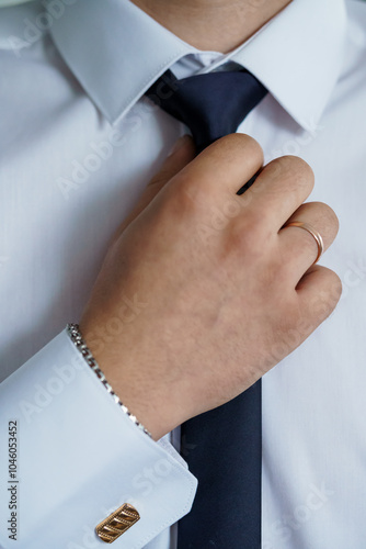 Elegant Business Attire: A Close-Up of a Man Adjusting His Tie