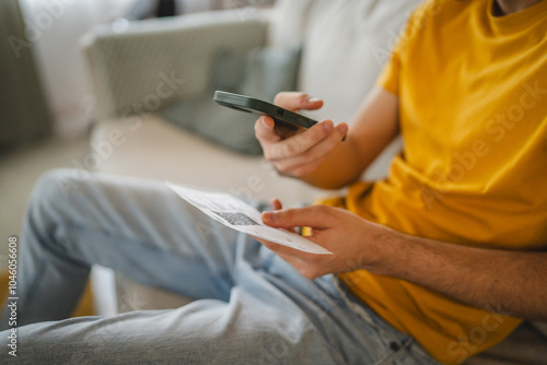 Close up of adult man have contactleess payment on cellphone at home