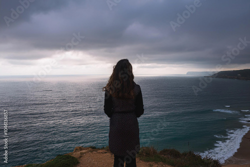 Mujer joven que se siente sola y triste  o pensativa o esperando. mirando el mar en un día sombrío , Young woman feeling alone and sad or thoughtful or waiting. looking at the sea on a gloomy day