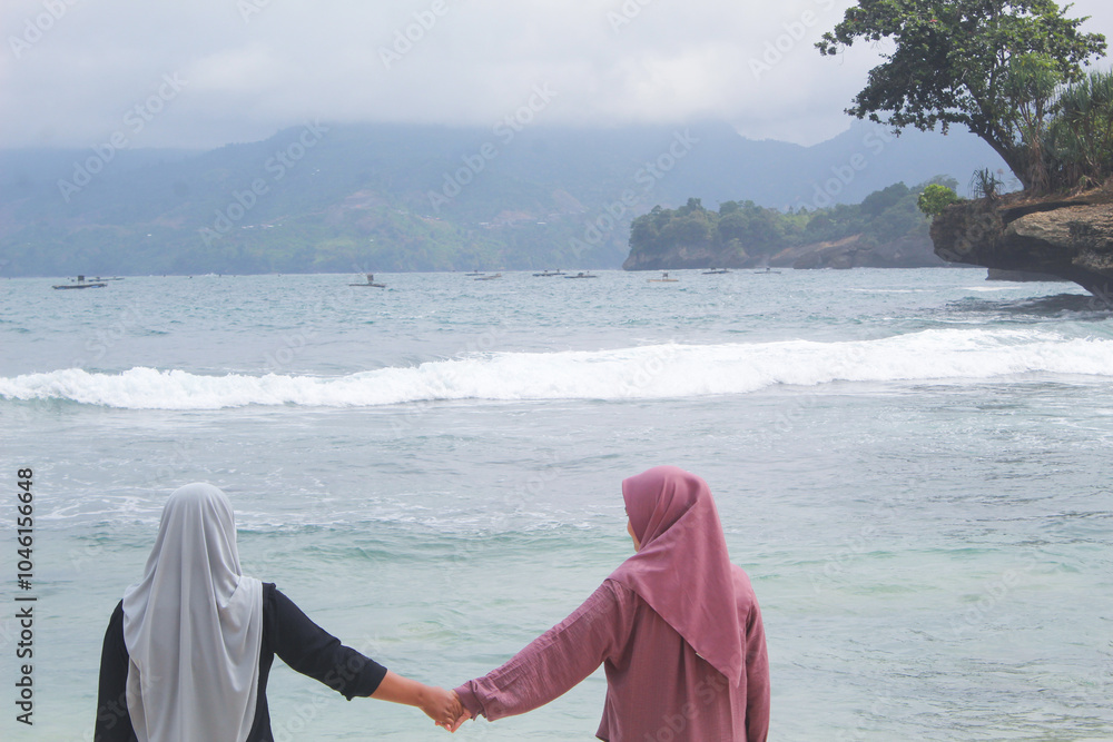 Two young women posing seen from behind with a beach background Two young women posing seen from behind with a beach background