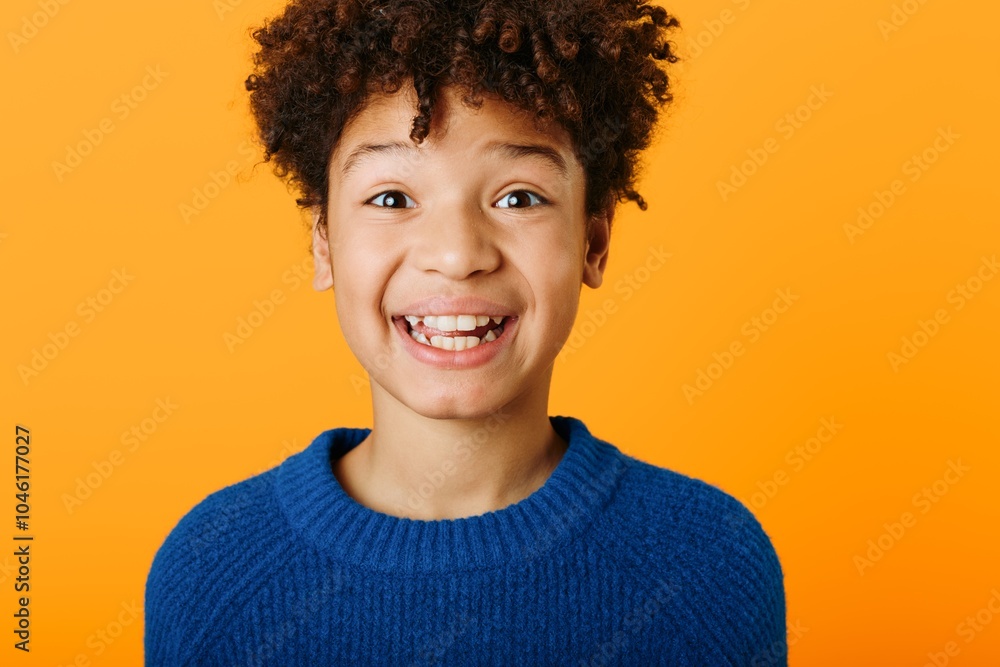 Joyful expression of a young african american boy radiating happiness against a vibrant orange background Joyful expression of a young african american boy radiating happiness against a vibrant orange background