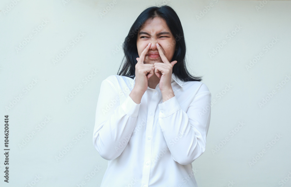 studio shot of dissappointed asian young woman executive wear formal white suit looking aside thinking about something with fingers touching her nose, standing