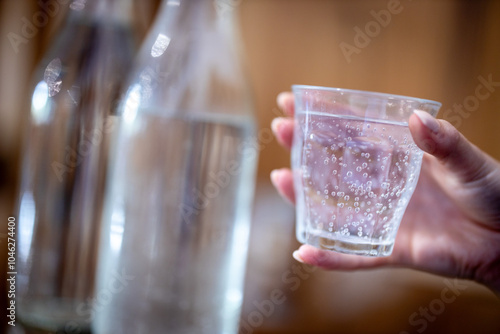 Holding glass of water at a cafe. Premium filtered water at a restaurant. Sparkling or still water, soda, mineral water or hydration options drinking from a glass. Close up view.