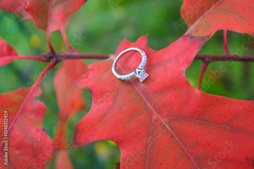 Elegant Wedding Ring Resting on a Bright Red Fall Oak Leaf: Symbol of Love and Autumn 