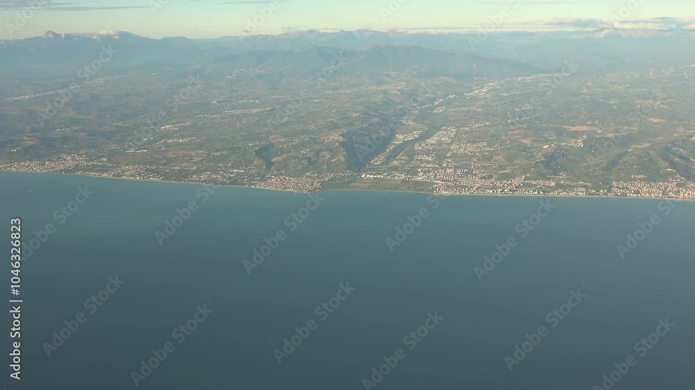 Aerial view of the Adriatic coast in Italy. View from the airplane window of the sea and hills. Earth's line. A perspective of the ground's colors and shapes Aerial view of the Adriatic coast in Italy. View from the airplane window of the sea and hills. Earth's line. A perspective of the ground's colors and shapes