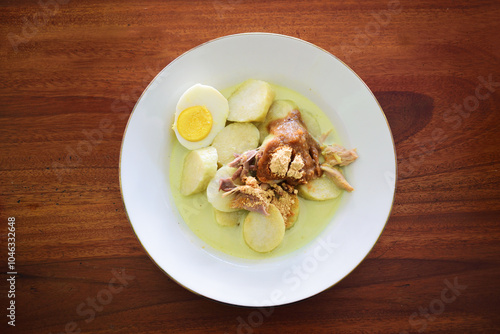 Top view of lontong opor, One kind of traditional Indonesian culinary food made from coconut milk, egg, rice cook or rice roll, chicken meat and powder photo