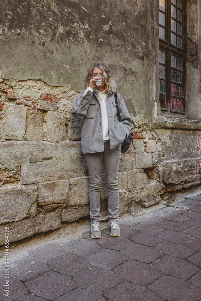 Young woman Girl near the wall. Real life. Old town. House facade. Peeled wall. Tourist route. Hoodie with the inscription Young woman Girl near the wall. Real life. Old town. House facade. Peeled wall. Tourist route. Hoodie with the inscription