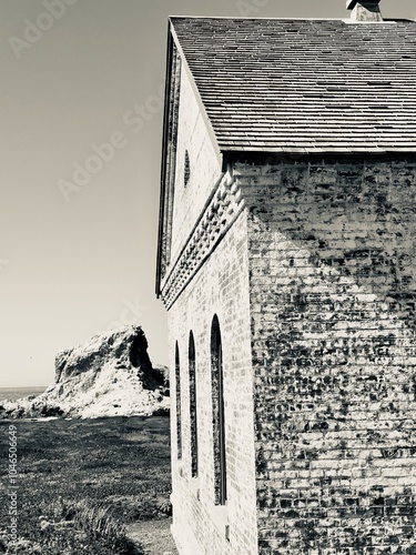 Принти на полотні A black and white capture of a former foghorn station's architectural details, with its distinctive arched windows and weathered brick walls set against a coastal sea stack