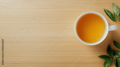 A warm cup of orange tea rests on a wooden table, accompanied by fresh green leaves, showcasing a cozy and inviting atmosphere.