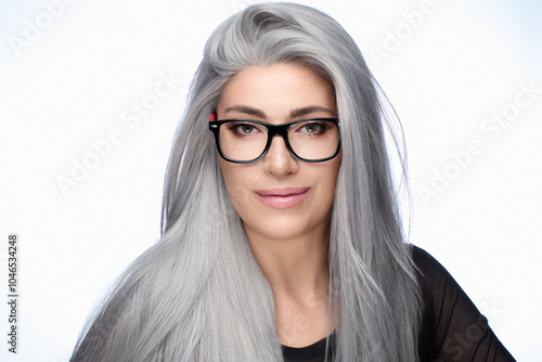 Photos Confident woman with long gray hair wearing stylish glasses, smiling against a w