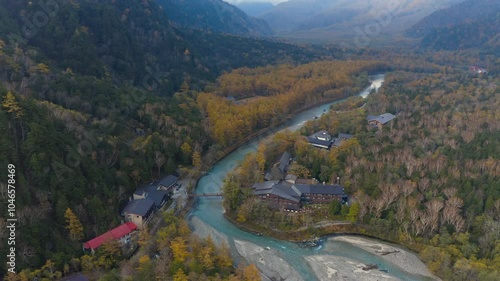 Aerial drone footage along river and Kappa bridge in Kamikochi Japan in Autumn season. Japanese nature travel destination tourist attraction national park scene.