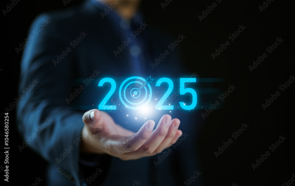 Set goals for 2025, businessman holds text 2025 with arrow target, implementation of business goals plan, development to achieve goals and success. Set goals for 2025, businessman holds text 2025 with arrow target, implementation of business goals plan, development to achieve goals and success.
