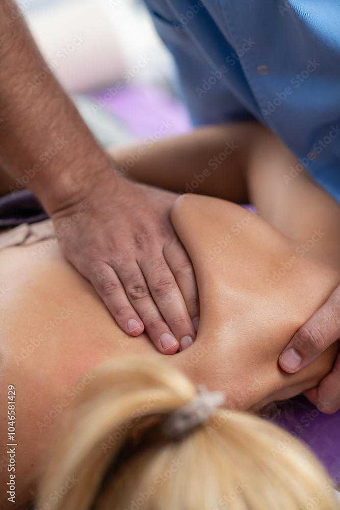 Physical therapist performs a deep tissue massage on a patients shoulder to relieve muscle tension and improve mobility in a therapeutic setting Physical therapist performs a deep tissue massage on a patients shoulder to relieve muscle tension and improve mobility in a therapeutic setting