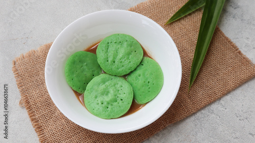 Serabi Pandan Kuah Kinca is Traditional Indonesia Pancake, Green Color from panda Paste. Served with Sweet Sauce Made from Coconut Milk and Palm Sugar photo