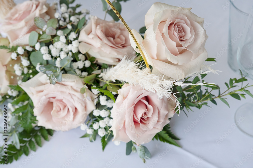 Elegant centerpiece set up on a dinner table, floral arrangement featuring soft blush-pink roses complemented by springs of greenery and white filler flowers, ethereal bouquet prepared for a wedding Elegant centerpiece set up on a dinner table, floral arrangement featuring soft blush-pink roses complemented by springs of greenery and white filler flowers, ethereal bouquet prepared for a wedding