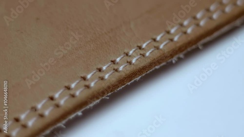 The edge of the brown leather product is stitched with double stitching. Closeup. Macro. Shallow depth of field. Shot in motion