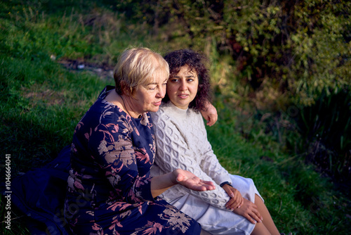 middle-aged daughter and an elderly mother together on a picnic in the autumn forest photo