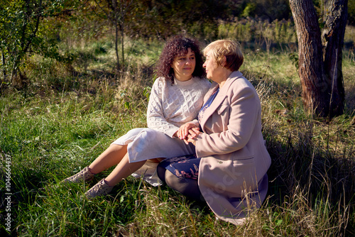 a   middle-aged daughter and elderly mother together on a walk in the autumn forest photo