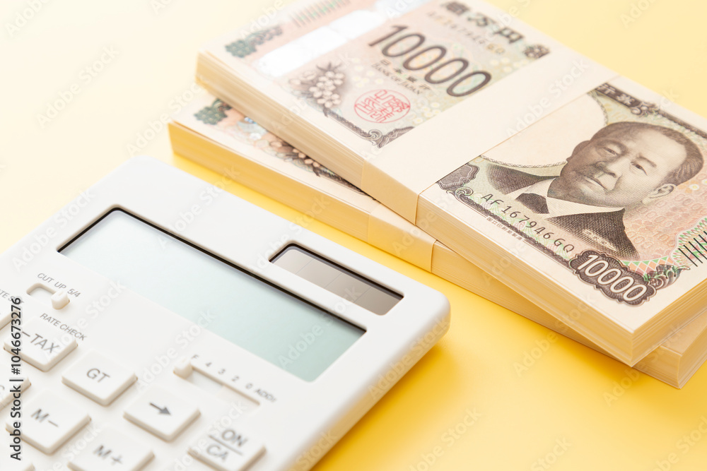 黄色背景に一万円の札束と電卓