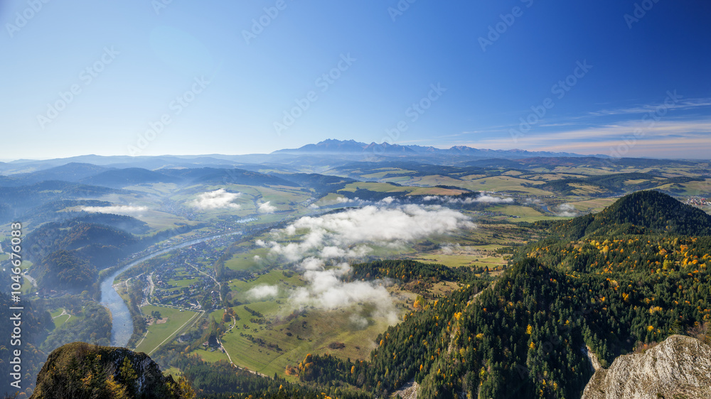 Beautiful mountain landscape. View from the Trzy Korony peak. The Tatra Mountains in the distance. The Dunajec River Valley. Autumn landscape. Clouds below the peaks. A winding river. Sromowce Niżne,