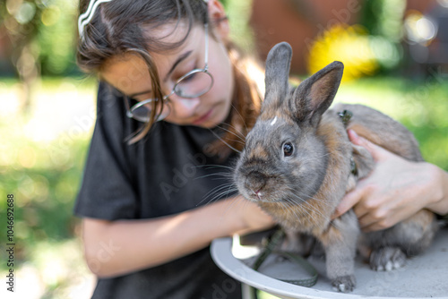 A girl plays with a domestic rabbit on the street. Pet concept. photo