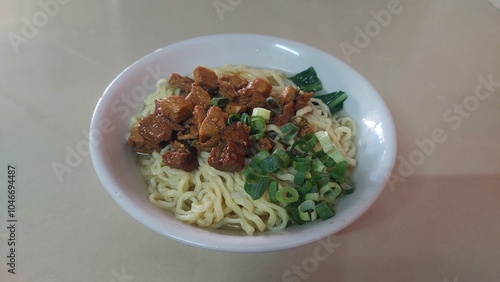 Indonesian chicken noodle soup with green onions.  This dish is a popular street food, perfect for a quick and flavorful meal.