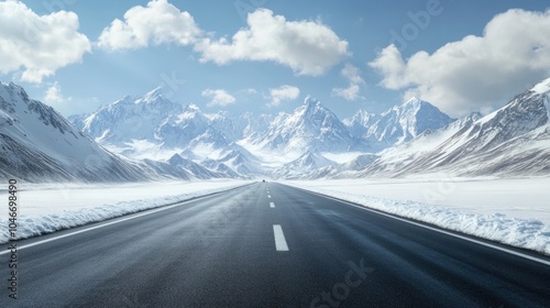 A scenic road stretches through snow-capped mountains under a clear blue sky.