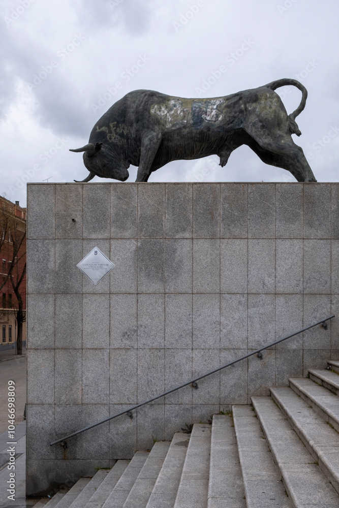 Bullfighting Building Madrid, Madrid - April 02, 2024: Bronze statue of a bull on a cloudy ...