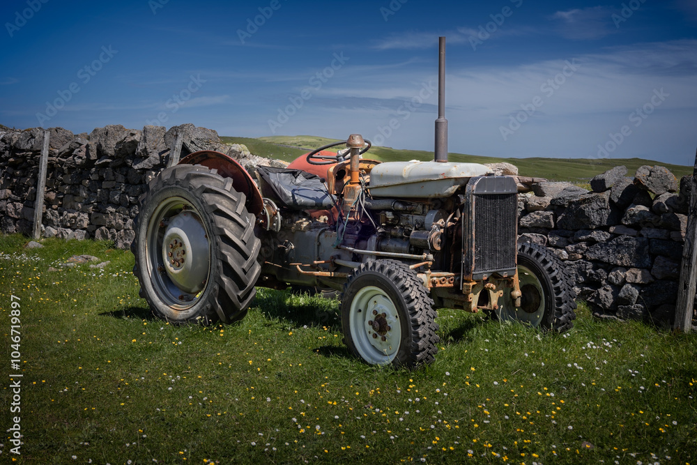 Obraz premium Old grey vintage farmer tractor on the land in a beautiful environment in Scotland, photo taken nearby Cape Wrath
