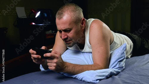 Man with smartphone in bed at night. Concept of insomnia and sleep disorders.