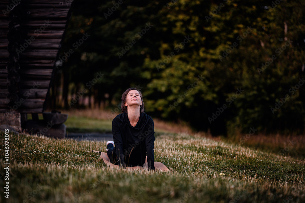 Fototapeta premium Woman practicing yoga outdoors in a serene setting