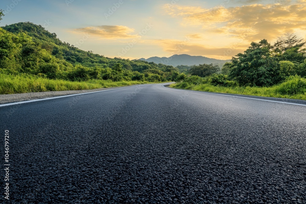 A winding asphalt road leading through a scenic landscape with green hills, lush vegetation, and a colorful sunset sky. A winding asphalt road leading through a scenic landscape with green hills, lush vegetation, and a colorful sunset sky.