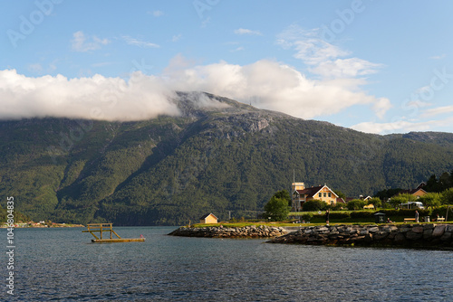Wallpaper Mural A scenic view of a sun-lit hut and a cloud-covered mountain by the Sognefjorden fjord in Norway on a warm, sunny day Torontodigital.ca