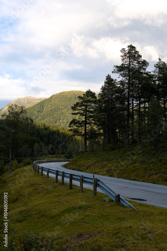 Wallpaper Mural A windy mountain road in the shadow with a sunlit mountain in the background on a warm, summer, overcast day in western Norway Torontodigital.ca