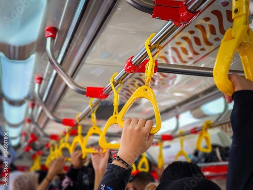 In the crowded train, a person was standing and holding a yellow handle hanging at the top of the train, the atmosphere of the trip during rush hour