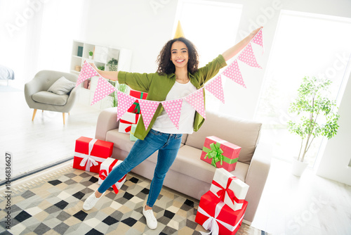 Photo of funny lovely positive girl holding flags preparing birthday party decorating house room dayligh indoors photo