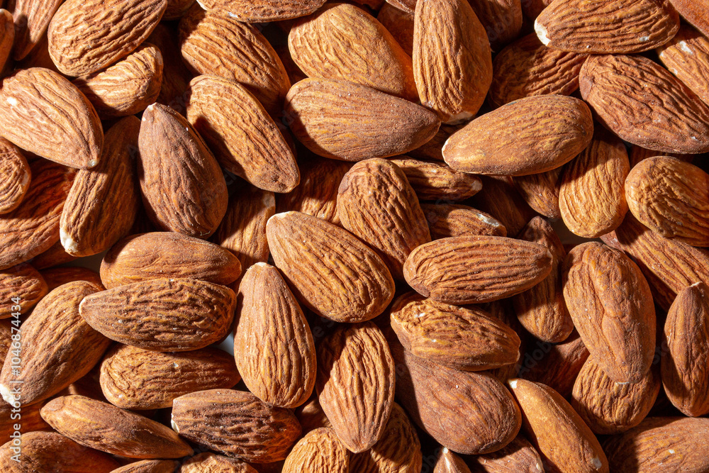 Fototapeta premium Scattered Almonds. Background from Almond Nuts. Natural High-Calorie Snacks