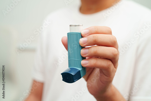 Asthma and chronic obstructive pulmonary disease COPD, Asian young man using metered dose inhaler MDI.