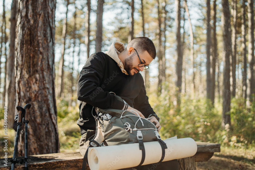 Fototapeta premium Young caucasian man drinking water taking break from hiking or trekking