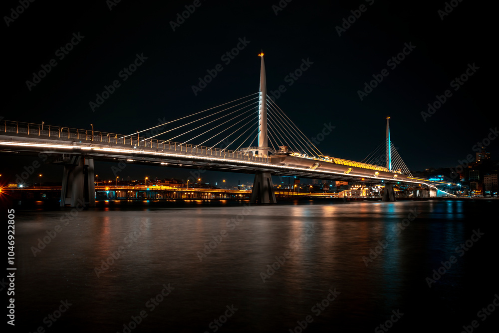 Fototapeta premium Istanbul, View of Illuminated Golden Horn Metro Bridge Over the Sea with City View in the Dark.