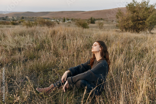 Meditative woman sitting in field with closed eyes gazing up at the vast sky photo