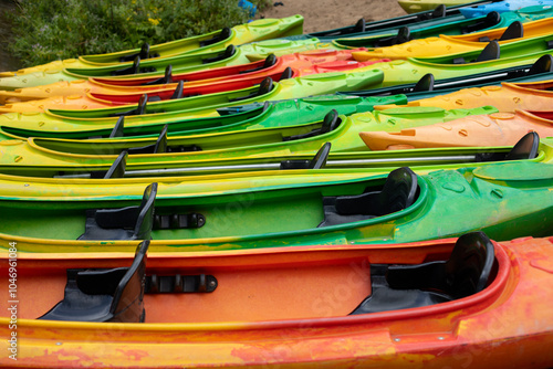 Multi-colored kayaks close-up on a sandy beach on a river, active outing concept, physical activity
