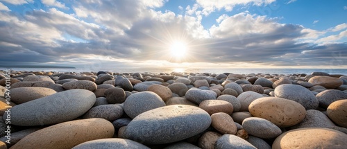 Bright sunlight breaking through clouds to illuminate a rock strewn beach photo