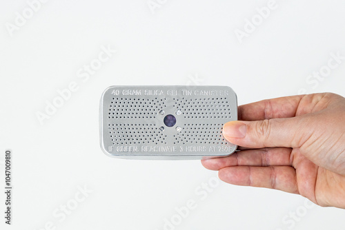 A hand holding a reusable silica gel canister, isolated on a white background photo