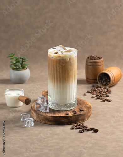 Iced Spanish Coffee: A glass of Iced Spanish Coffee with a creamy blend of espresso and milk, served with ice cubes, coffee beans, and a small milk jug on a wooden board.