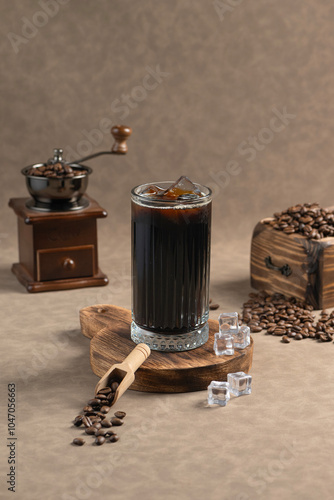 Iced Americano: A glass of black Iced Americano on a wooden board, accompanied by ice cubes and scattered coffee beans. A coffee grinder and bean chest sit in the background.