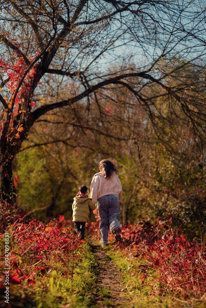 A mother and son run through the forest, enjoying quality weekend time together, playing outdoors in the countryside. A mother and son run through the forest, enjoying quality weekend time together, playing outdoors in the countryside.