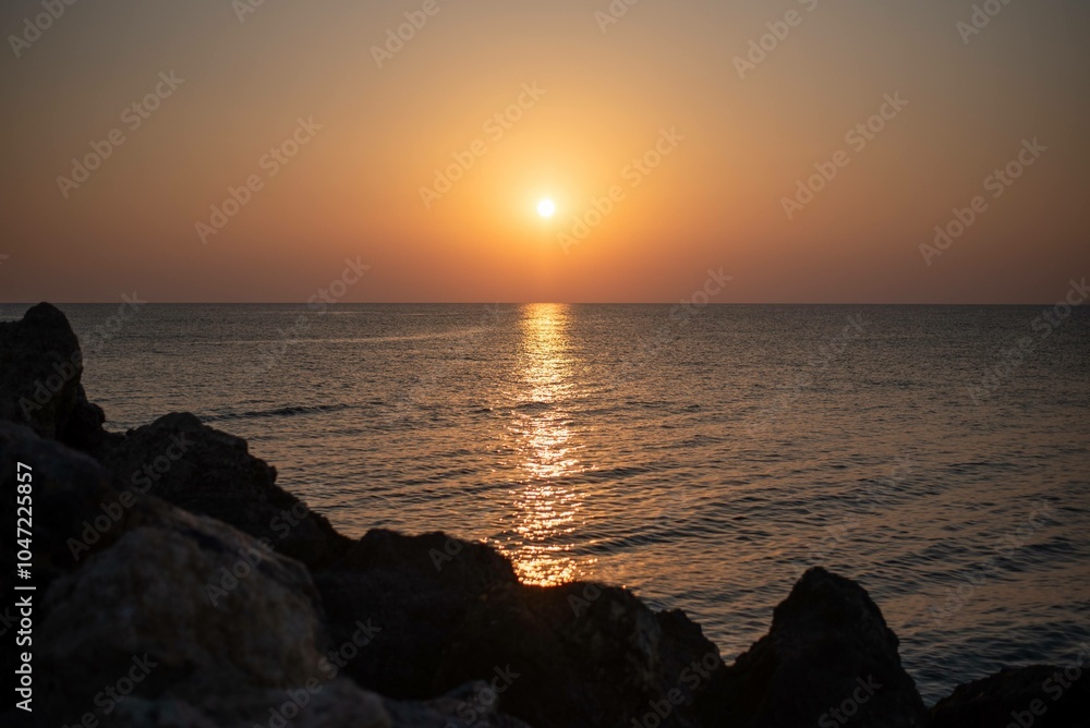 A stunning sunrise over the sea on the island of Crete, Greece. The calm waters reflect the golden hues of the morning sky, creating a peaceful seascape.