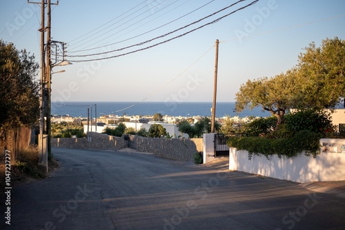 Narrow Greek streets in Hersonissos, Crete, Greece, lined with charming whitewashed buildings, colorful flowers, and vibrant local shops, exuding charm. photo