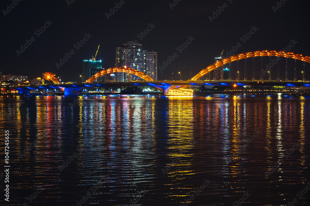 Naklejka premium Panorama of Dragon Bridge or Cau Rong Bridge over the Han River in Da Nang in Vietnam at night with a golden backlight